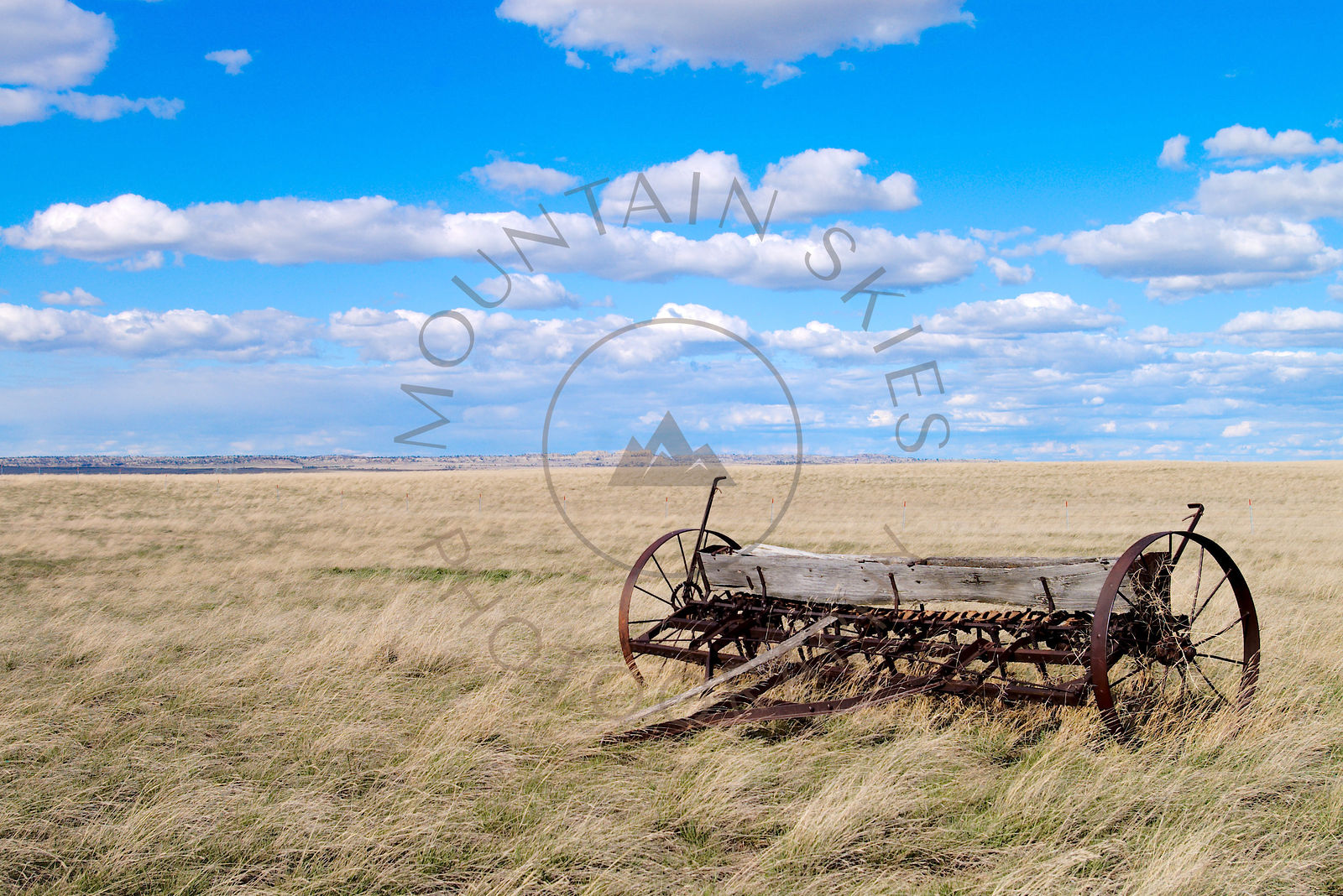 Old farm wagon in an open grassland beneath blue skies